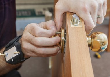 Installing interior door, carpenter installs knob using magnetic bracelet tool. clipart