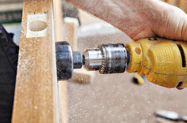 Hang a door, carpenter drillings lock latch hole, close-up.