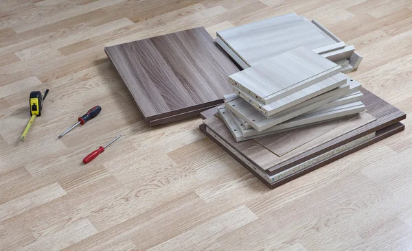 Spånskivor för montering möbler liggande på golvet bredvid skruvmejsel. — Stockfoto