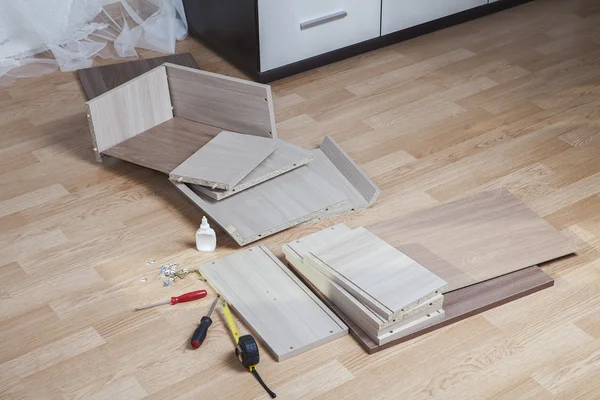 Dát dohromady vlastní sestavení nábytku dřevotřískové desky části leží na podlaze. — Stock fotografie