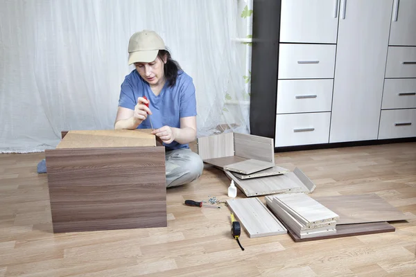 Montaje de muebles, la mujer monta mesa de noche atornillar hardboard a marco de madera . — Foto de Stock