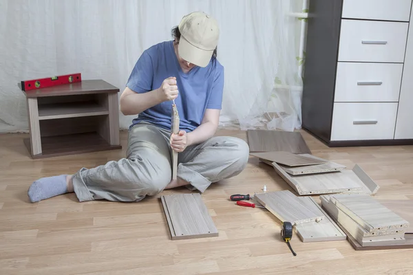 Montar muebles de madera, una mujer aplica pegamento al borde del aglomerado . —  Fotos de Stock