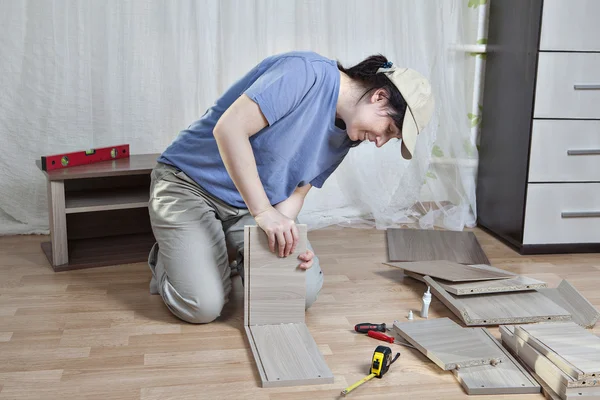 Montaggio mobili in legno, donna incolla parte del cassetto, sul pavimento . — Foto Stock