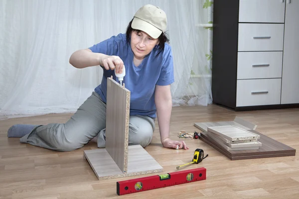 Мебельная сборка, женщина смазывает поверхность клеевого ДСП . — стоковое фото