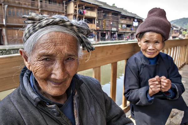 Oude Aziatische boer vrouw laat rusten op een bankje in het Chinese platteland. — Stockfoto