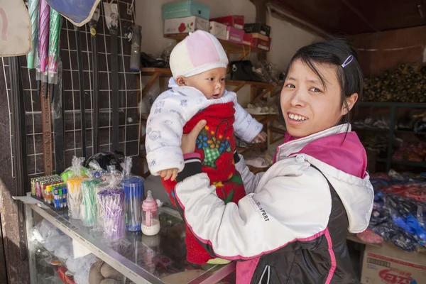 Chica joven china comerciante sosteniendo un bebé en las manos . — Foto de Stock