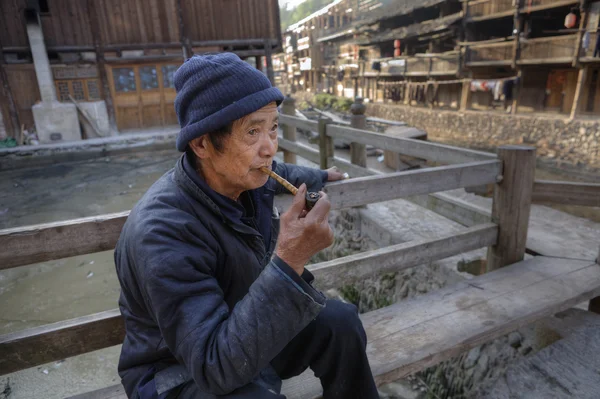 Homme chinois âgé tient dans sa main pipe en bambou fumant . — Photo