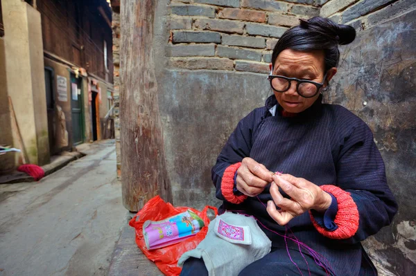 Femme asiatique avec des lunettes est engagée dans la broderie à l'extérieur, en Chine . — Photo