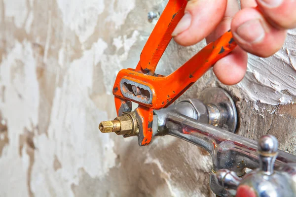 Close-up of hands plumber turning tap valve with red pliers. — Stock Photo, Image