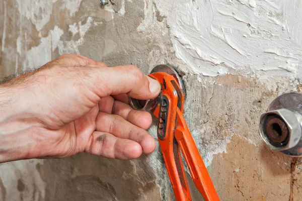 Närbild händer VVS justerar positionen av excentrisk tap med röd tång. — Stockfoto