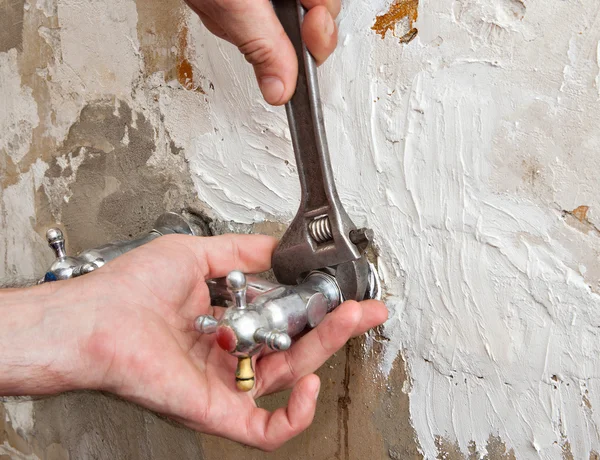 Verstelbare kraan, professionele loodgieter van de handen met water kraan en spanner — Stockfoto