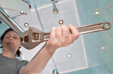 Woman removing old tap aerator using an adjustable plumbing spanner. clipart