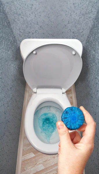 Hand hält festes Waschmittel in Toilettenschüsseltank. — Stockfoto