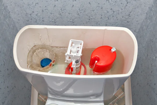 Limpiador azul tableta soluble en agua cae en el tanque de descarga del inodoro . —  Fotos de Stock
