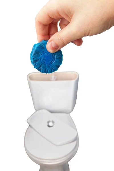 Ręka trzyma niebieskie tabletki czyszczące nad spustowy zbiornika toalety. — Zdjęcie stockowe