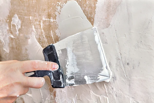 Painter puttied wall using a paint scraper, hand close-up. Stock Image