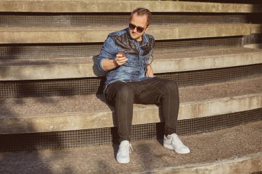 Akıllı telefonlu bir Rus merdivenlerde oturuyor..