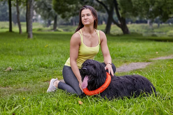 Svart briard kramas av sin kvinnliga ägare på friluftsliv på sommaren. — Stockfoto