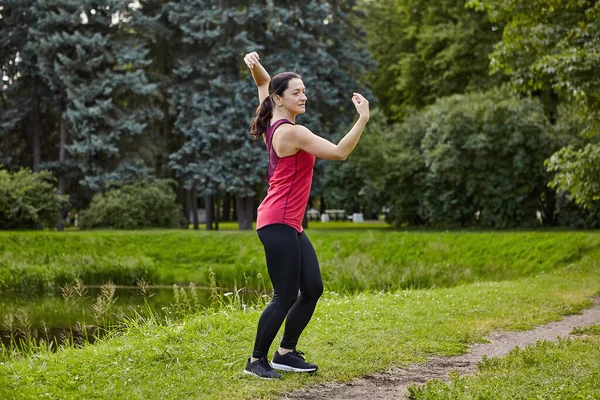 Mujer atlética está haciendo ejercicio en el jardín de la ciudad por la mañana. — Foto de Stock