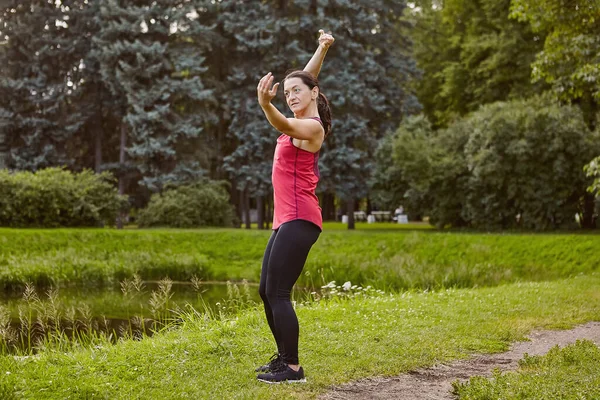 White serious lady is making exercises in public park at morning. — Stock Photo, Image