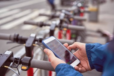 Adam açık havada elektrikli scooter kiralamak için QR kodunu tarıyor..