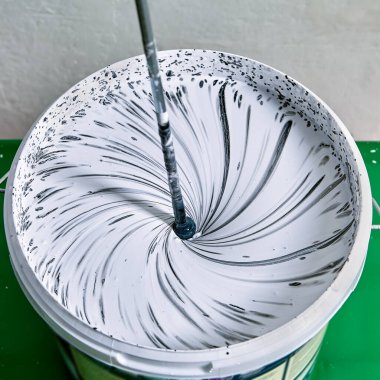 Ressam, duvarları boyamak için boyaları çırpıcı ile birleştirir.