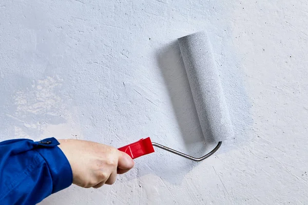 Мастер покраски стены с помощью ролика краски во время ремонта дома. — стоковое фото