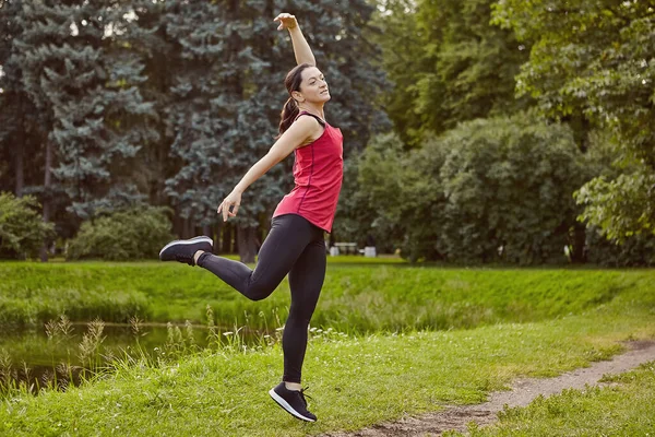 池の横に公園で体操をする若い女性. — ストック写真