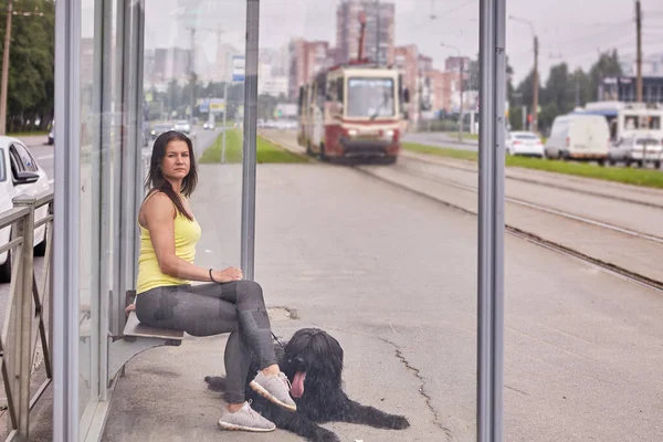 Zwarte briard en vrouw wachten op tram op het openbaar vervoer station. — Stockfoto