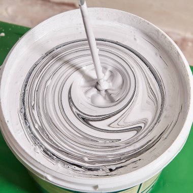 Ressam, yenileme sırasında duvarı boyamak için boyaları mikserle karıştırıyor. İşçi çalışma aracı ile yeni renk yapar.