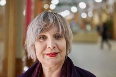 Ticaret galerisinde gülümseyen orta yaşlı çekici bir kadının portresi. Alışveriş merkezinde yetişkin bir kadın 60 yaşında..