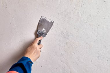 Ev ressamı daha küçük çatlakları kapatıyor ve delikler, macun bıçağıyla alçılama bileşimine baskı yapıyor. Çatlağın delikleri ya da çatlakları doldurduğundan emin oluyor..