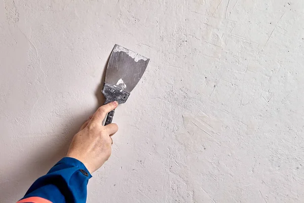 Home painter is patching smaller cracks and holes presses the spackling compound across surface imperfections with a putty knife, making sure spackle fills the holes or crack.