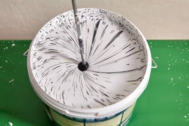 Tamirci, yenileme sırasında evdeki duvarları boyarken karıştırıcı kullanarak sepetteki renkleri karıştırıyor. Tamirci yeni boya yapıyor..