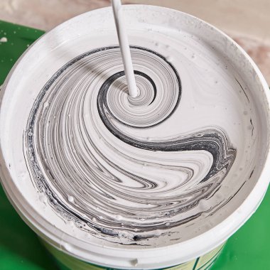 Evdeki tamirci tarafından yenilenirken duvarları boyamak için matkapla sepetteki renklerin karıştırılması.