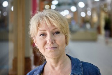 Ticaret galerisinde sarı saçlı, ciddi, güzel, yaşlı bir kadın..