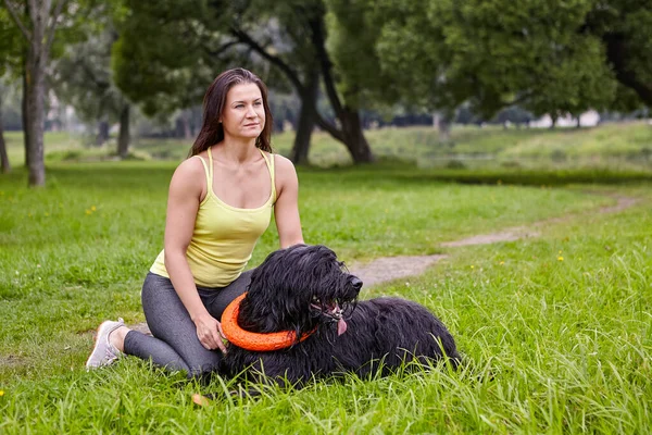 Briard med svart hår ligger på gräs i parken med kvinnlig ägare. — Stockfoto