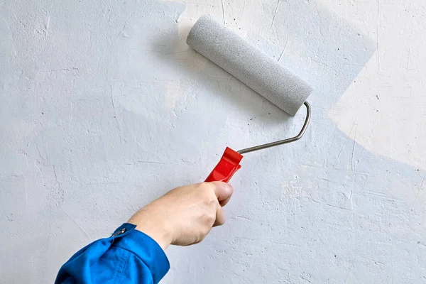 Handyman utiliza pinturas y rodillos de pintura para pintar la pared. — Foto de Stock