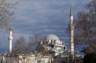 İstanbul, Türkiye - 12 Şubat 2020: Fatih ilçesindeki Beyazit Camii, kara bulutlar altında güneşle aydınlandı.