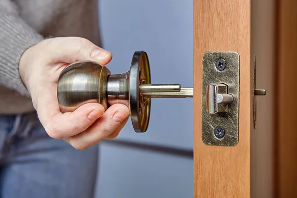 Handyman pushes the door knob spindle through the face bore and the latch assembly.