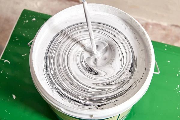 房屋油漆工使用电钻和桨搅拌器将黑白油漆混合 使其呈灰白色 — 图库照片