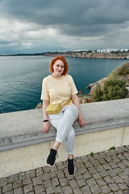 Antalya 'da ilkbaharın başlarında, genç Avrupalı kadın denizin önündeki gözetleme noktasının korkuluklarında oturur..