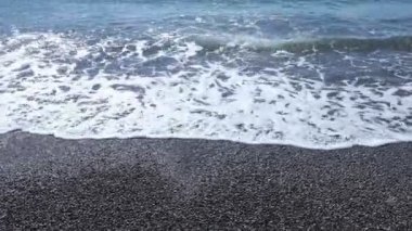 Deniz dalgaları bir çakıl taşı kumsalı ile kıyıya vurur..