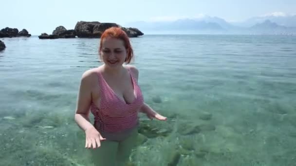 Una joven europea se encuentra en aguas frías transparentes en una playa pagada en Antalya al comienzo de la temporada turística, a principios de primavera. — Vídeos de Stock