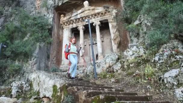 Escadaria de pedra que leva a túmulos lícios em Fethiye, peru, jovem mulher desce com paus de caminhada. — Vídeo de Stock