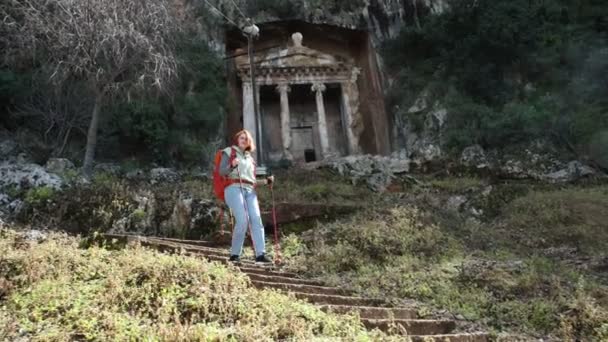 European tourist walks down hillside after visiting Lycian rock tombs in Fethiye, Turkey, in early spring. — Stock Video
