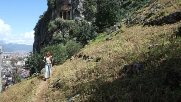 Fiatal európai nő sétál le a dombról a turistapóznák hátterében város Fethiye Törökországban. — Stock videók