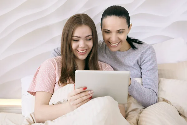 Мама з донькою - підлітком дивиться фільм на планшетному екрані в ліжку.. — стокове фото