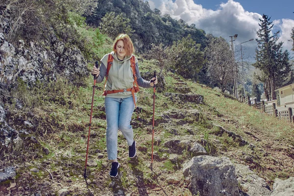 背着背包的徒步旅行者在山坡上行走时，用登山杆子从山上下来. — 图库照片