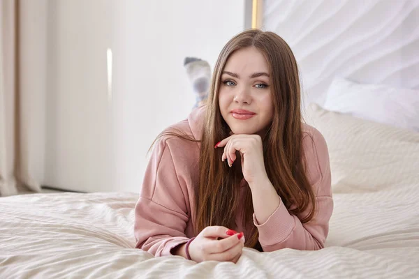 Jovem mulher branca jaz na cama em seu estômago, close-up retrato. — Fotografia de Stock